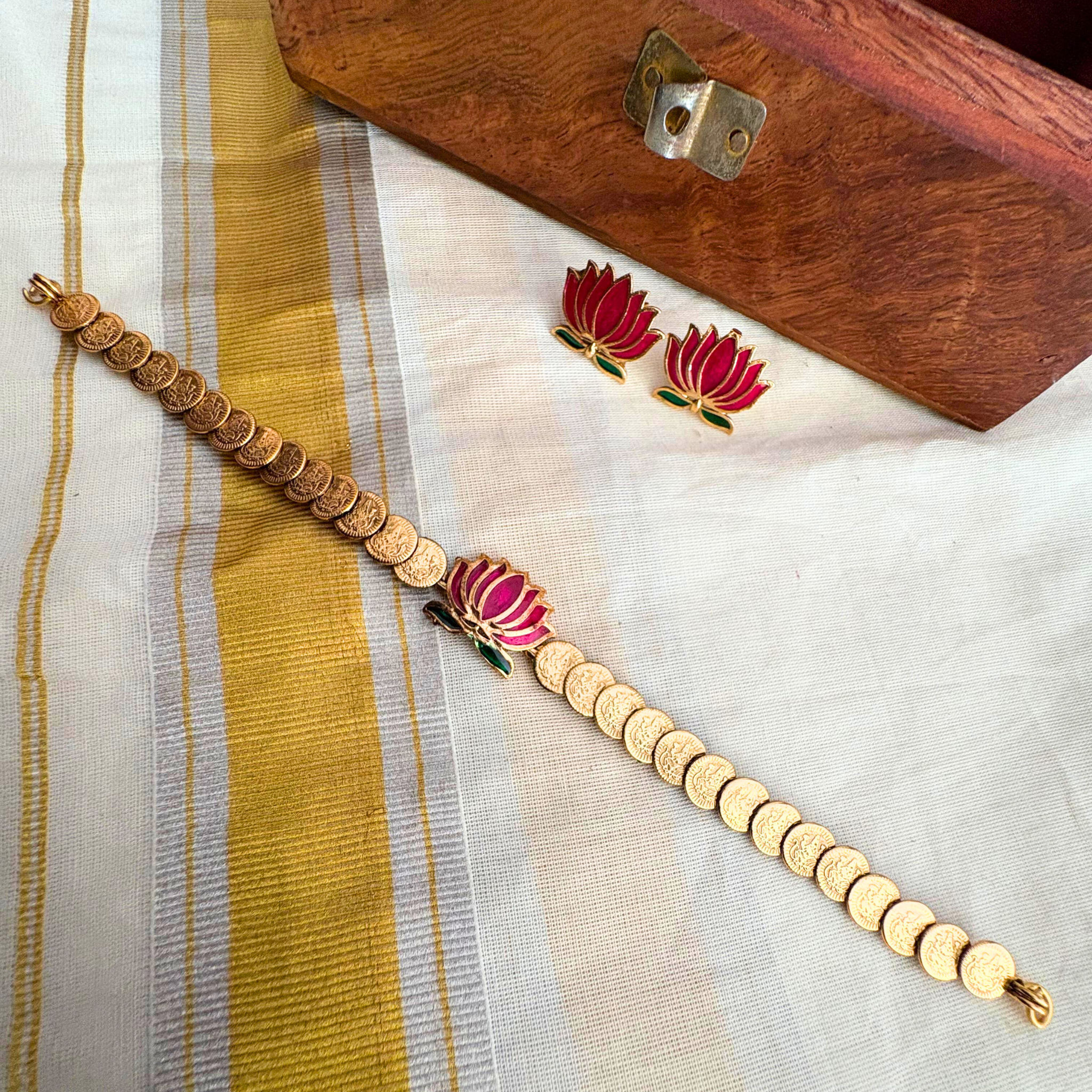 Traditional Kerala Lakshmi Kasu Mala coin necklace with a pink lotus centerpiece and matching lotus studs on a Kasavu fabric background