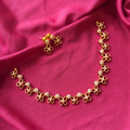 Modern gold finish necklace with four-petal floral motifs and white AD stone clusters on a dark pink fabric background